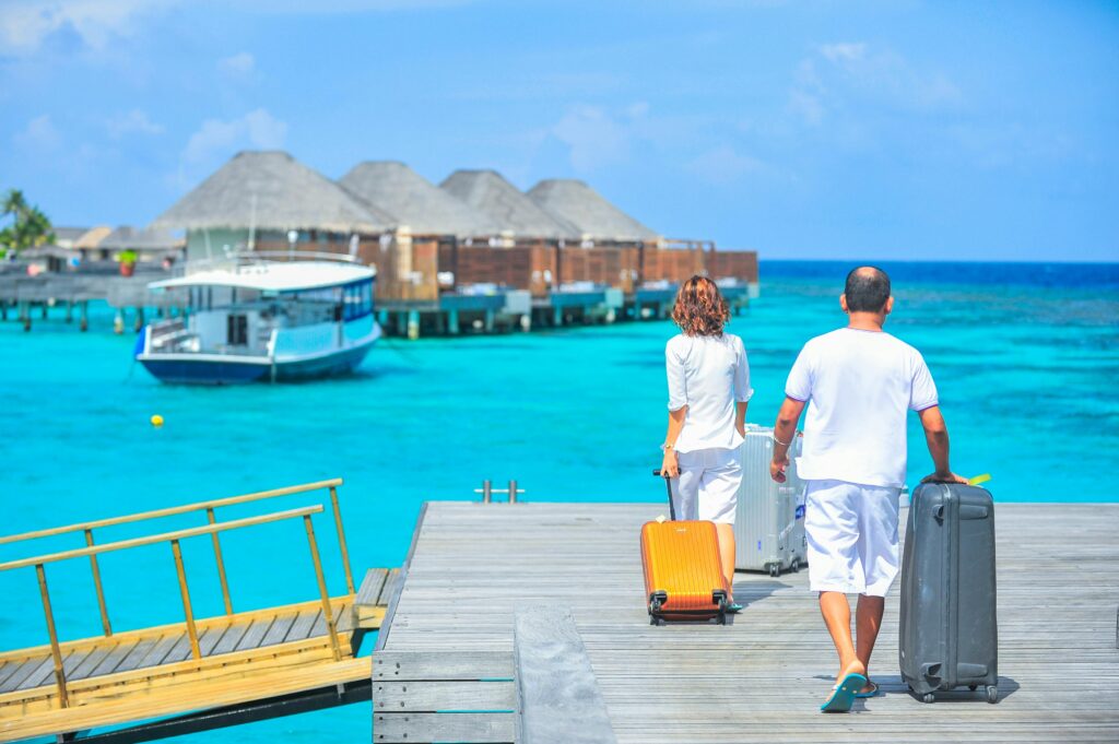 A couple arriving at a luxurious Maldives resort dock with luggage, capturing a tropical vacation vibe.